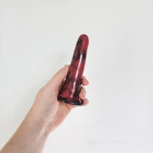 Load image into Gallery viewer, A hand holds a 5 inch classic ceramic dildo in red with a black bubble pattern in front of a white background.

