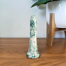Load image into Gallery viewer, A 6 inch classic ceramic dildo in a dark green bubble pattern stands on a wooden table against a white background. A plant in a white pot with a wooden stand is to the right.
